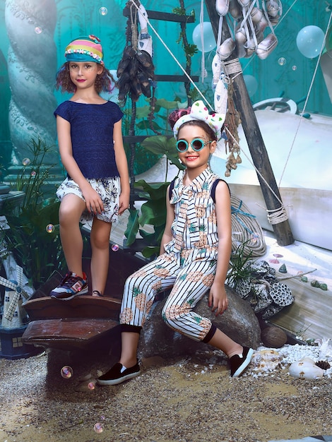 Foto dos chicas están sentadas en una roca y una lleva gafas de sol y la otra lleva una camisa azul.