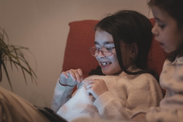 Dos chicas están viendo una película mientras están sentadas en el sofá.