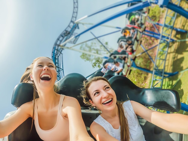 Dos chicas felices divirtiéndose en la montaña rusa