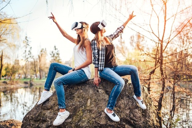 Dos chicas guapas disfrutan de gafas de realidad virtual al aire libre.