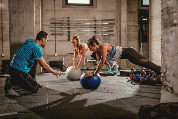 Dos chicas haciendo ejercicio con un entrenador personal en el gimnasio.