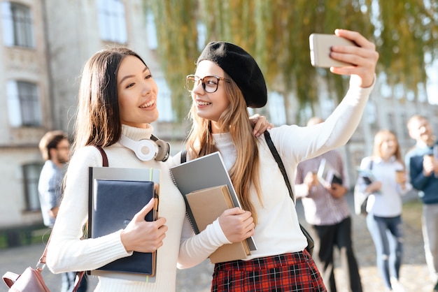 Dos chicas haciendo selfie en el patio de la universidad.