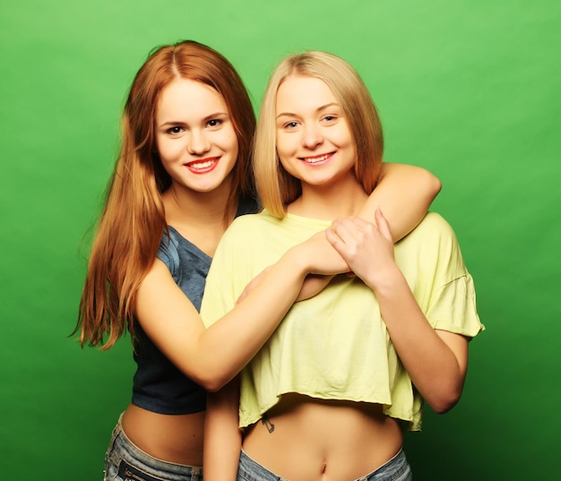 Dos chicas hipster mejores amigas sobre fondo verde
