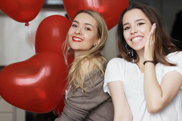 Dos chicas jóvenes están celebrando el Día de San Valentín. Están sonriendo.