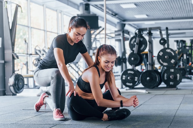 Dos chicas jóvenes en ropa deportiva están juntas en el gimnasio durante el día.