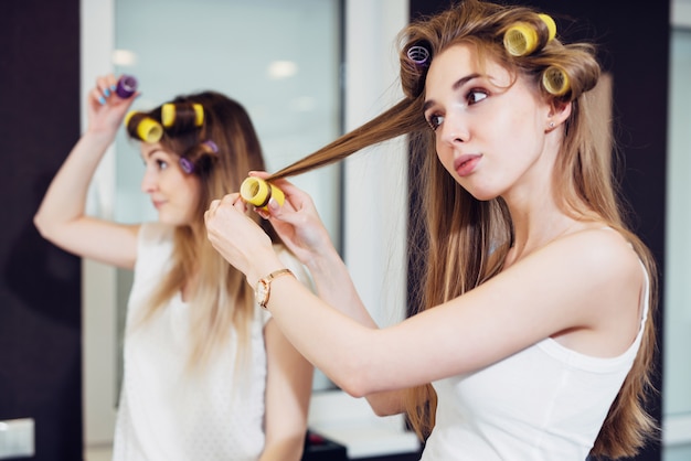 Dos chicas llenándose el cabello con rulos en una habitación