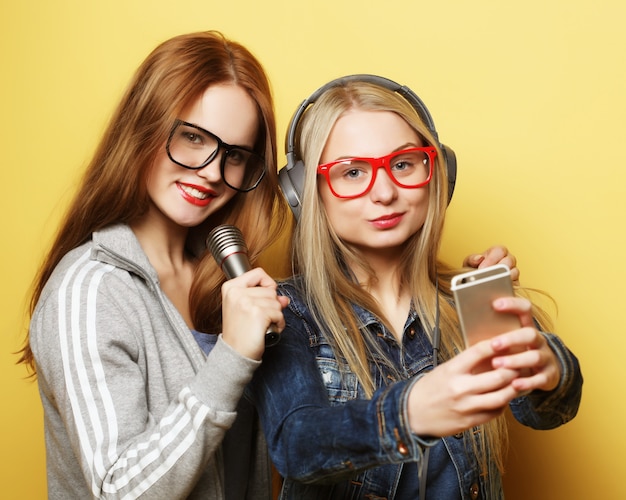 Dos chicas con un micrófono cantando y divirtiéndose juntas, hacen selfie