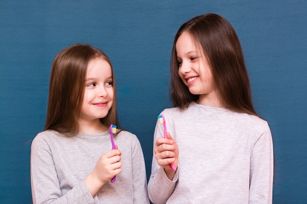 Dos chicas mirándose y sosteniendo cepillos de dientes en sus manos