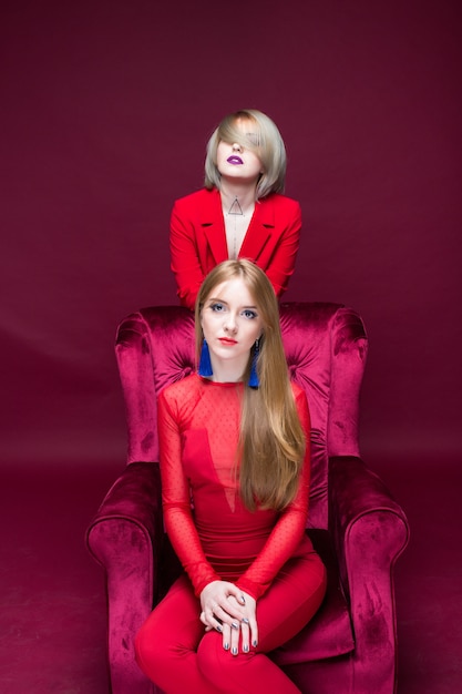 Foto dos chicas mujer en ropa roja ubicación silla roja y fondo rojo