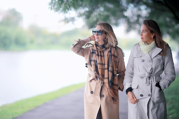 dos chicas del parque de la moda de otoño miran / caminan en un parque de la ciudad dos novias glamorosas de moda en un abrigo