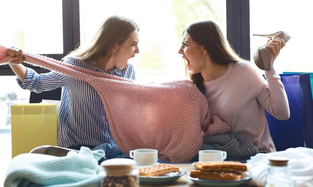 Dos chicas peleando por un suéter rosa y gritándose en el café después de ir de compras