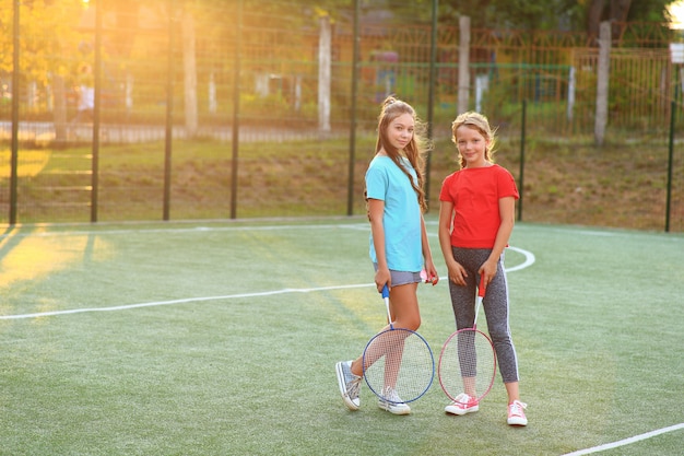 Dos chicas con raquetas de bádminton en el campo de fútbol.