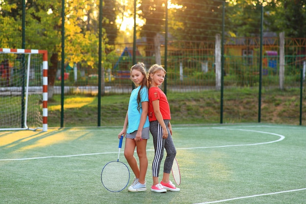 Dos chicas con raquetas de bádminton en el campo de fútbol.