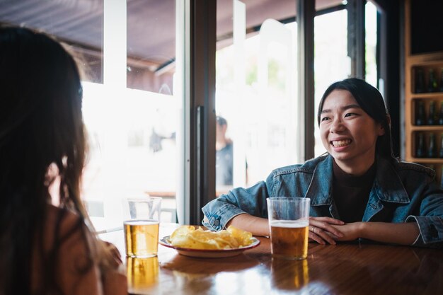 Dos chicas riéndose charlando y pasando un buen rato sentadas en un bar