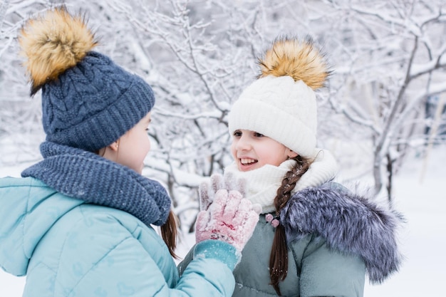 Dos chicas sonrientes con ropa de abrigo se reunieron en un parque nevado Estilo de vida de paseos de invierno