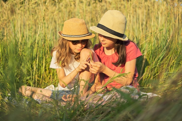 Dos chicas sonrientes sentados en el césped, niños hablando