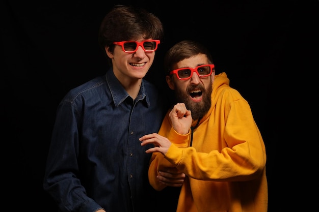 Dos chicos y una chica en un cine miran emocionalmente una película Cine Chicos jóvenes con gafas 3D