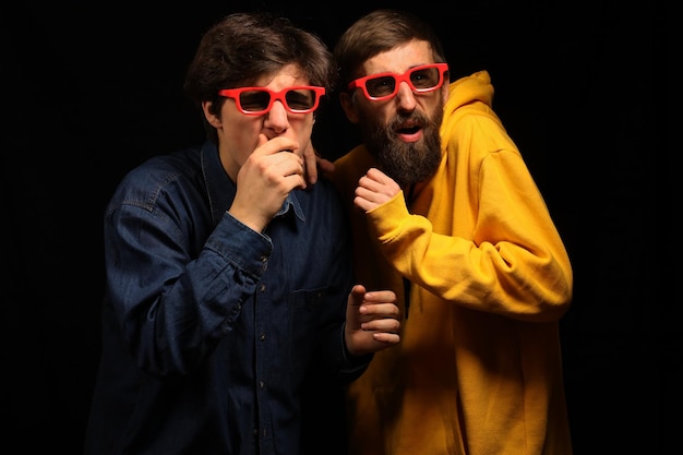 Dos chicos y una chica en un cine miran emocionalmente una película Cine Chicos jóvenes con gafas 3D