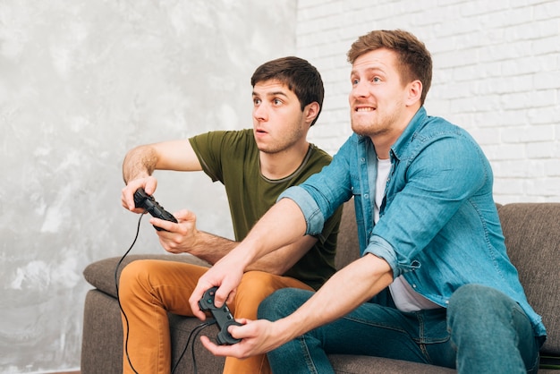 Dos chicos jugando en la consola sentados en el sofá.