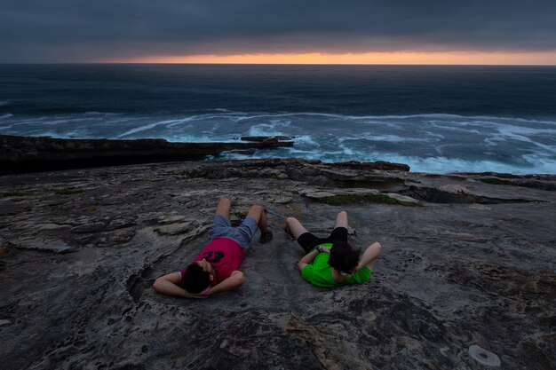 Dos chicos mirando la puesta de sol en la costa de la montaña Jaizkibel, junto a Hondarribia, País Vasco.