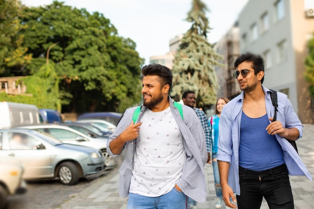 Dos chicos con mochilas caminando y hablando al aire libre.