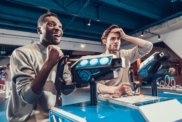 Dos chicos pilotando naves espaciales en arcade.