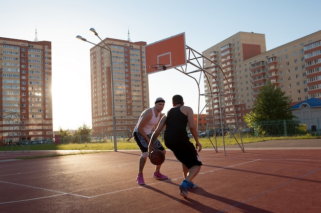 Dos chicos saltando se estiran hacia la pelota en la cancha de baloncesto