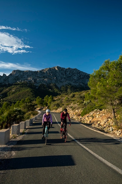 Dos ciclistas alrededor del pueblo de Calpe con la montaña Bernia al fondo Alicante España