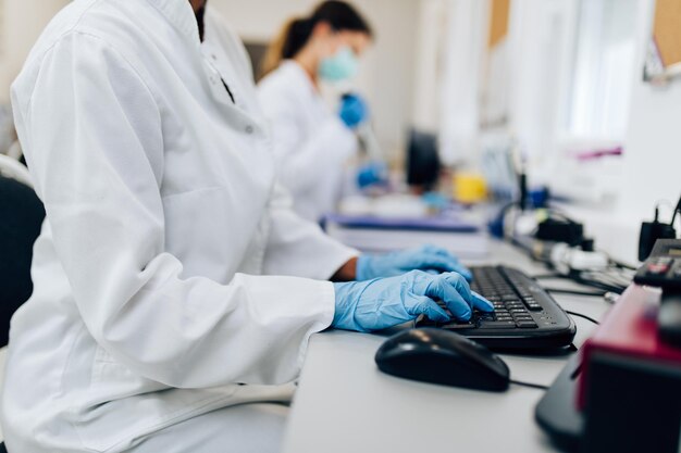 Dos científicas o técnicos con máscaras protectoras faciales trabajan en laboratorio con muestras de sangre humana.