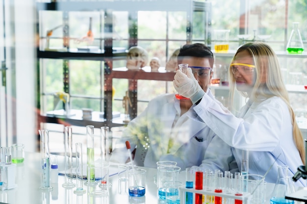 Dos científicos que miran el resultado de las pruebas médicas en un tubo de vidrio mientras realizan investigaciones en el laboratorio de ciencias