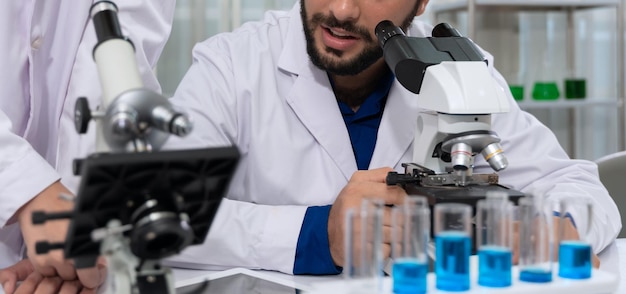 Dos científicos trabajando juntos en laboratorio y discutiendo experimentos con microscopio