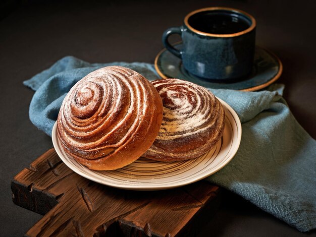 Dos cinnabons de azúcar en polvo en un plato blanco con una taza de té