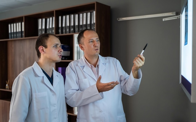 Dos cirujanos mirando la película de rayos X diagnosticando la enfermedad del paciente en el hospital Concepto médico Discutiendo problemas médicos