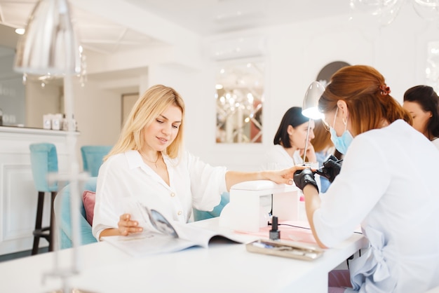 Dos clientes en procedimiento de manicura en salón de belleza.