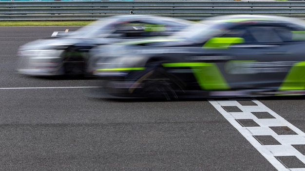 Foto dos coches de carreras luchan en la pista de carreras cruzando a la línea de meta dos autos de carreras compiten