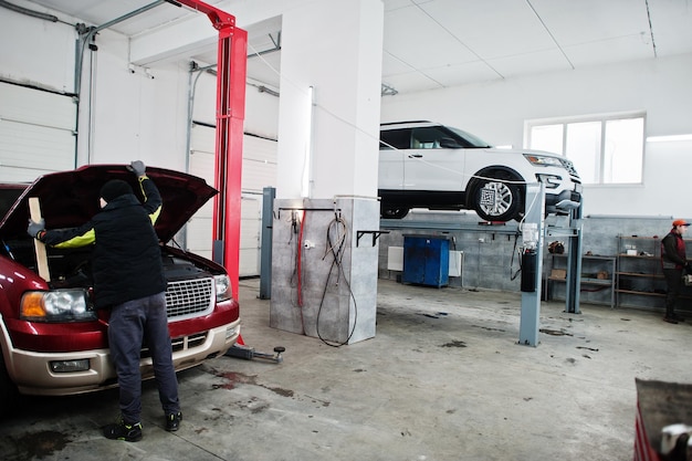 Dos coches todoterreno americanos en el stand para comprobar la inclinación de la alineación de las ruedas en el taller de la estación de servicio