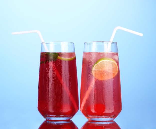 Dos cócteles de cereza con hielo sobre fondo azul oscuro