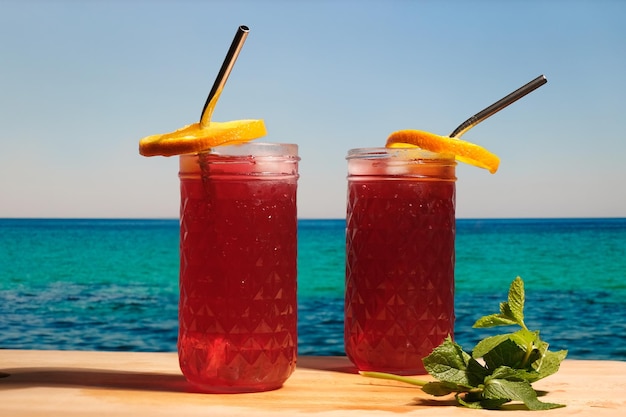 Dos cócteles de ron con jugo de arándanos en la playa tropical