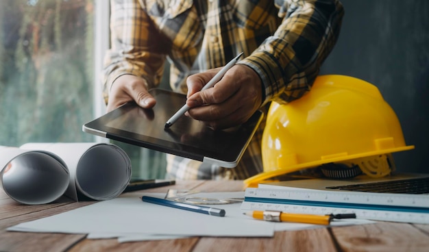 Dos colegas discuten el trabajo de datos y una tableta portátil con un proyecto arquitectónico en el sitio de construcción en el escritorio de la oficina