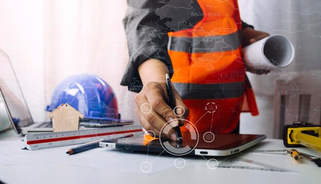 Dos colegas discuten el trabajo de datos y una tableta portátil con un proyecto arquitectónico en el sitio de construcción en el escritorio de la oficina