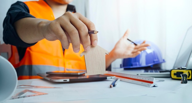 Dos colegas discutiendo el trabajo de datos y la tableta portátil con un proyecto arquitectónico en el sitio de construcción en el escritorio de la oficina