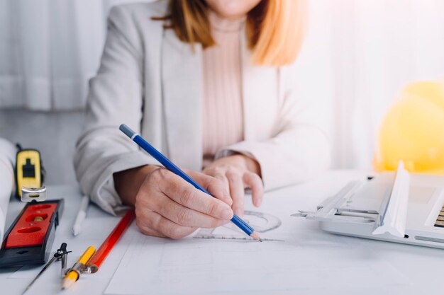 Dos colegas discutiendo el trabajo de datos y la tableta portátil con un proyecto arquitectónico en el sitio de construcción en el escritorio de la oficina