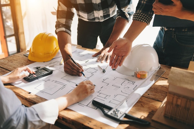 Dos colegas discutiendo el trabajo de datos y la tableta portátil con un proyecto arquitectónico en el sitio de construcción en el escritorio