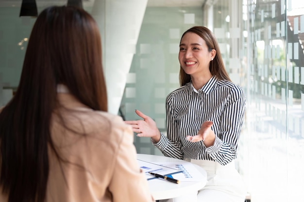 Dos colegas empresarias asiáticas se reúnen para asistir a una conferencia de inversores profesionales que trabajan y discuten un nuevo proyecto de estrategia empresarial de marketing Concepto financiero y contable empresarial