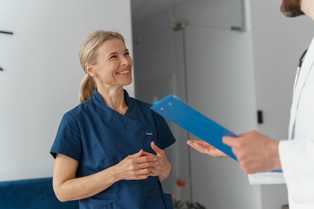 Dos colegas médicos discutiendo el puesto de diagnóstico del paciente en la sala de la clínica