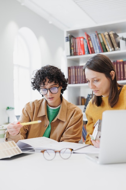 Foto dos colegas mujeres trabajan en computadoras portátiles en la biblioteca de la oficina de coworking alumnas exitosas