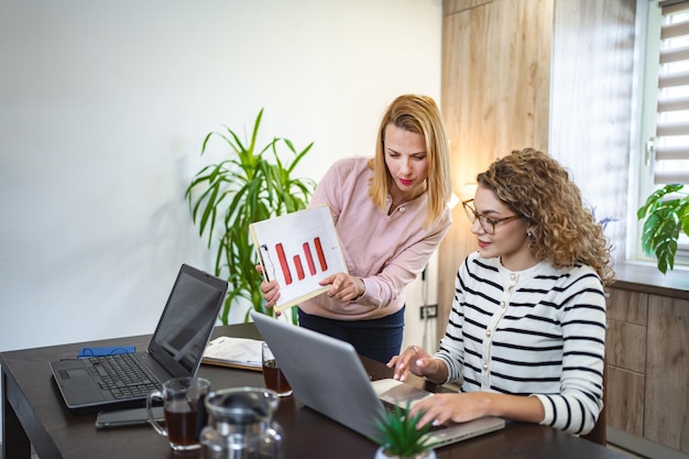 Dos colegas mujeres trabajando juntas en un informe de negocios