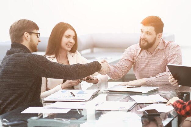 Dos colegas de negocios dándose la mano durante la reunión