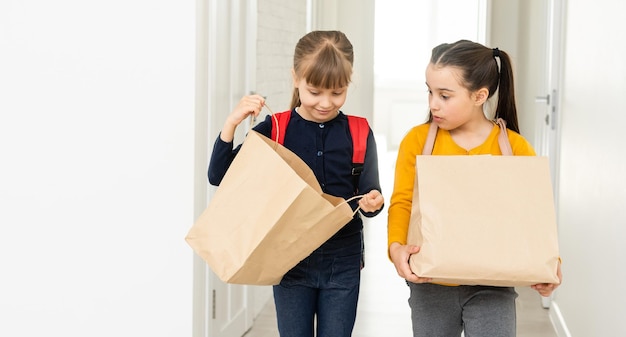 dos colegialas con mochila y paquetes de entrega manos en fondo blanco.