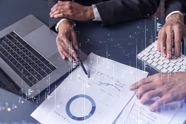 Dos comerciantes, un hombre y una mujer, investigan datos históricos para predecir el comportamiento del mercado de valores Concepto de comercio por Internet Forex y gráfico de holograma financiero sobre la mesa con los documentos